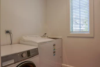 Laundry with washer, dryer and tub at Butterfly Cottage