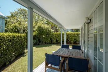 Outdoor deck with table and chairs overlooking the private garden at Bellbird Cottage