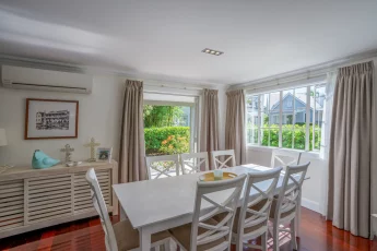 Sunlit dining area with table, chairs and french doors opening to the private garden at Capital Cottage
