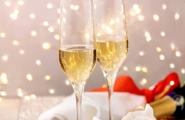 table-setting-with-two-champagne-glasses-berry-meringue-desserts-tray-standing-silver-sparkling-table-white-hearts-bokeh-lights_72772-20067